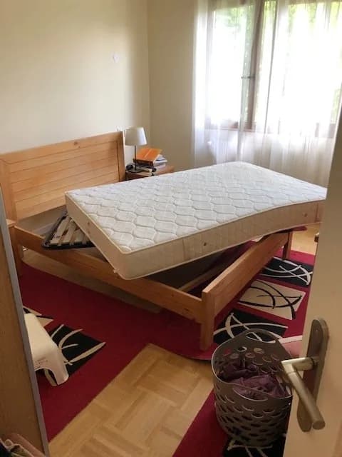 Chambre préparée avant intervention, matelas relevé et posé de champ sur le cadre du lit