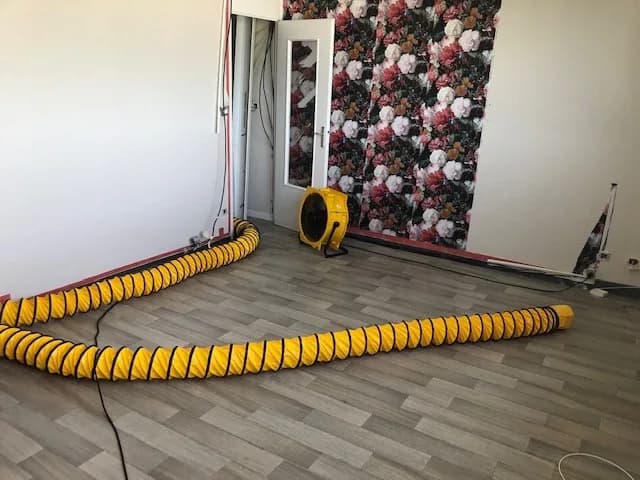 Gaine souple traversant une pièce jusqu'à une turbine placée contre le mur du fond