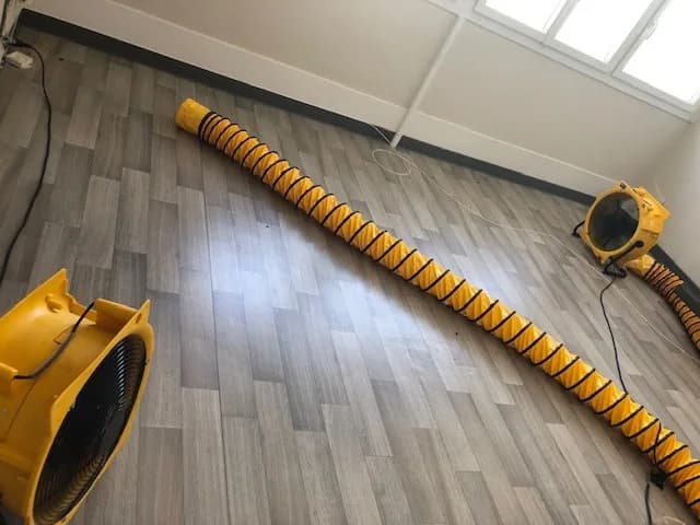 Pièce vidée de son mobilier, gaine souple déployée au sol entre deux turbines de brassage