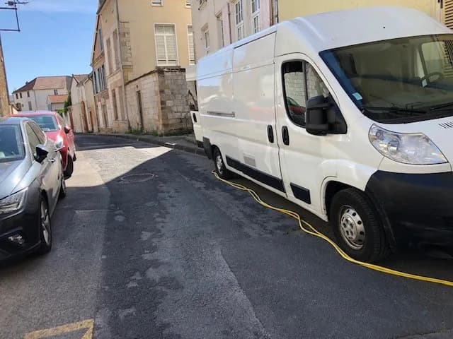 Fourgon utilitaire stationné dans une rue, câble d'alimentation déroulé depuis l'arrière du véhicule